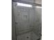 Walk-in shower with glass doors, white marble-like tiles, and built-in shelf at 4823 Riverside Dr., North Myrtle Beach, SC 29582