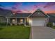 Charming single-story home with a well-manicured lawn, inviting front porch, and attached two-car garage at sunset at 505 Joy Way Ct., Longs, SC 29568