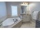 A bathroom with a corner jacuzzi tub, undermount sink with a granite countertop, and a large mirror at 616 Edgecreek Dr., Myrtle Beach, SC 29579
