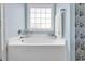 Bright bathroom features a large soaking tub under a window, with light blue walls and stylish accents at 732 American Beech St., Loris, SC 29569