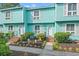Charming two-story townhome with a turquoise exterior, well-maintained landscaping and welcoming front entrance at 7403 N Ocean Blvd. # C, Myrtle Beach, SC 29572
