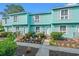 Charming townhomes with aqua siding, white shutters, landscaped yard, and brick steps leading to the front door at 7403 N Ocean Blvd. # C, Myrtle Beach, SC 29572