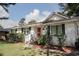 Charming single-story home with a metal roof, white painted brick, black shutters, manicured bushes, and a red front door at 1014 Bay Dr., Surfside Beach, SC 29575