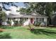 Charming single-story home featuring a metal roof, white painted brick, well-manicured landscaping, and a vibrant red front door at 1014 Bay Dr., Surfside Beach, SC 29575