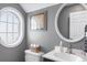Bright bathroom with a unique round window, elegant toilet, modern sink, and stylish round mirror at 104 Clovis Circle, Myrtle Beach, SC 29579