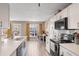 Modern kitchen features white cabinets, stainless steel appliances, and a breakfast bar with views to living area at 104 Clovis Circle, Myrtle Beach, SC 29579