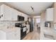 Clean kitchen with white cabinets, black appliances, and stone countertops offering an easy transition to dining room at 104 Clovis Circle, Myrtle Beach, SC 29579