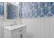 Charming powder room with blue palm wallpaper, white wainscoting, and vanity with white countertop at 116 Chapel Ridge Circle, Myrtle Beach, SC 29588