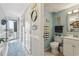 A hallway view opens to a bright bathroom with blue walls and white cabinets, complemented by a fluffy rug at 1210 N Waccamaw Dr. # 1105, Murrells Inlet, SC 29576