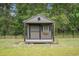 The shed features a window with shutters, a porch, and a grey paint job with black trim at 1476 Burriss Rd., Conway, SC 29526