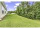 Grassy backyard featuring a well-maintained lawn, mature trees, and a screened-in porch at 191 Marley Blue Dr., Little River, SC 29566