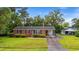 A quaint brick home enhanced by a lush green lawn, driveway, carport, and detached garage at 203 Longwood Ln., Conway, SC 29527