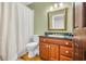 Traditional bathroom with wooden cabinets, green marble countertop, classic mirror, and a shower with white curtain at 2382 Waverly Rd., Pawleys Island, SC 29585