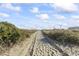Sandy path leading to the beach with natural vegetation on either side under a blue sky at 2616 Hillbourne Loop, North Myrtle Beach, SC 29582