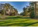 Expansive golf course view with lush green fairway, mature trees, and a clear blue sky at 3334 Cedar Creek Run, Little River, SC 29566