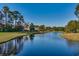 Tranquil scene of a golf course and pond surrounded by lush trees and a clear blue sky at 3334 Cedar Creek Run, Little River, SC 29566