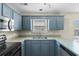The U-shaped kitchen features a stainless steel sink, blue cabinets, modern appliances, and natural light at 4013 Blackwolf Dr., Myrtle Beach, SC 29579