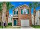 Charming two-story home with brick facade, teal accents, an attached garage and mature palm trees at 422 South Poplar Dr., Surfside Beach, SC 29575