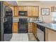 Efficient kitchen layout with wood cabinets, black appliances, and a view of a scenic map on the wall at 4574 Girvan Dr. # D, Myrtle Beach, SC 29579