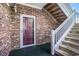 Inviting brick condo entrance with a burgundy door, wooden stairs, white railings, and clear unit number signage at 5751 Oyster Catcher Dr. # 315, North Myrtle Beach, SC 29582