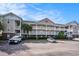 Three-story condo building with a beautiful facade, exterior staircases, and a well-kept parking area under a bright blue sky at 5751 Oyster Catcher Dr. # 315, North Myrtle Beach, SC 29582