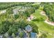 Aerial view of condos with a golf course, pool, and tennis court amidst lush, green trees at 598 Blue Stem Dr. # 52E, Pawleys Island, SC 29585