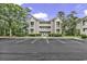 Three-story condo complex, ample parking, and mature trees create an inviting, peaceful setting at 598 Blue Stem Dr. # 52E, Pawleys Island, SC 29585