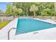 A bright community pool and lounging deck lined with palm trees is surrounded by forest and fencing at 598 Blue Stem Dr. # 52E, Pawleys Island, SC 29585