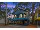 Charming blue two-story coastal home on stilts with a spacious front porch and dusk sky at 6001 - 1737 S Kings Hwy., Myrtle Beach, SC 29575