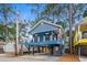 Charming blue two-story coastal home on stilts with a spacious front porch and clear blue sky at 6001 - 1737 S Kings Hwy., Myrtle Beach, SC 29575