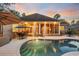 Backyard swimming pool featuring a fountain and a screened-in porch with comfortable seating at dusk at 81 Cascade Dr., Murrells Inlet, SC 29576