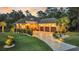 Elegant brick home featuring a three-car garage, manicured lawn, and inviting curb appeal at dusk at 81 Cascade Dr., Murrells Inlet, SC 29576