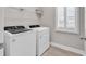 Well-organized laundry room with modern washer and dryer units, overhead shelving, and natural light from a shuttered window at 8469 Cape Dutch Loop, Myrtle Beach, SC 29572