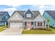 Charming two-story blue home with a two-car garage, a coral colored front door, and lush landscaping at 1008 Mary Read Dr., North Myrtle Beach, SC 29582
