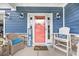 Inviting front porch with wicker chair, seating and coral front door creating a warm and welcoming entrance at 1008 Mary Read Dr., North Myrtle Beach, SC 29582