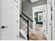 Hallway with staircase, white trim, and hardwood floors leads to naturally lit rooms, showcasing the home's layout at 103 Pigeon Forge Ct., Murrells Inlet, SC 29576