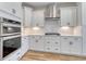 Modern kitchen boasts white cabinets, a stylish tile backsplash, stainless steel hood, and wood grain flooring at 1083 Laconic Dr., Myrtle Beach, SC 29588