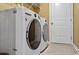 A laundry room features a washer and dryer with a tile floor and white door at 1631 Hepburn Dr., Little River, SC 29566
