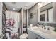 Cozy bathroom featuring floral-themed shower curtain, neutral-toned walls, and a framed mirror above the sink at 1990 N Waccamaw Dr. # 1008, Murrells Inlet, SC 29576