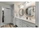 Bright bathroom featuring dual sinks, white cabinets, framed mirrors, and an adjacent walk-in closet at 2020 Willow Run Dr. # D, Little River, SC 29566