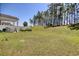 Large, grassy backyard featuring a covered patio, white fencing, and beautiful landscaping at 212 Carolina Lakes Blvd., Myrtle Beach, SC 29588