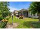 Well-maintained backyard featuring a screened porch, colorful flower beds, and lush green lawn under a blue sky at 2318 Via Palma Dr., North Myrtle Beach, SC 29582