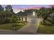 Charming home exterior highlighted by warm lighting, lush landscaping, and a well-maintained lawn at twilight at 2318 Via Palma Dr., North Myrtle Beach, SC 29582