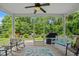 Covered screened porch offers a relaxing retreat with fan, seating, and views of the lush greenery and outdoor grill at 2318 Via Palma Dr., North Myrtle Beach, SC 29582
