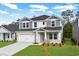 Charming two-story home with white brick, gray accents, manicured lawn and an attached garage at 2610 Tranquility Loop, Longs, SC 29568