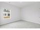 Neutral bedroom featuring neutral carpet, white walls, and a window view of backyard at 2700 Tranquility Loop, Longs, SC 29568