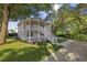 Charming two-story home featuring a spacious porch and staircase surrounded by lush green trees and landscaping at 409 2Nd Ave. S, Myrtle Beach, SC 29577
