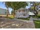Charming two-story home featuring a spacious porch and staircase surrounded by lush green trees and landscaping at 409 2Nd Ave. S, Myrtle Beach, SC 29577
