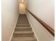 Carpeted staircase featuring a wooden handrail and light walls leading to the upper level at 5059 Sundrop Ln., Little River, SC 29566