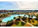 Aerial view of a large community pool with tropical palm trees, cabana and water views in the distance at 5718 Herring Gull Circle, North Myrtle Beach, SC 29582